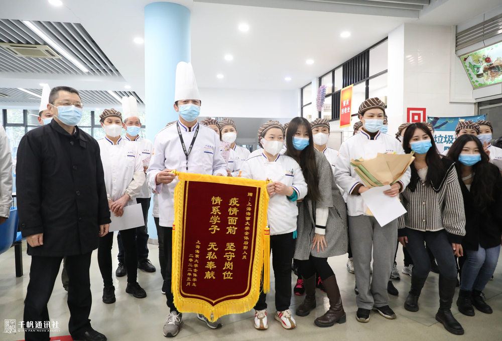 陸靖校長與同學(xué)代表一起向食堂工作人員送上鮮花和錦旗